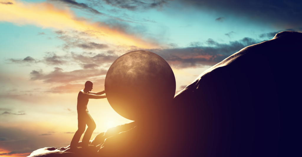 Man pushes a boulder up a hill like the myth of Sisyphus